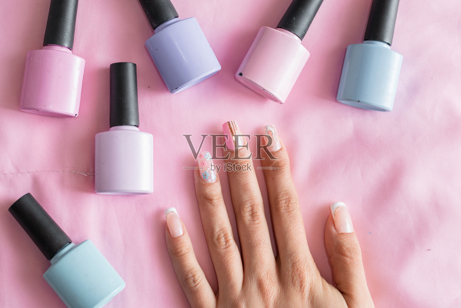 一个女人的手的详细视图,在粉红色的背景上画着指甲和彩色指甲油照片摄影图片