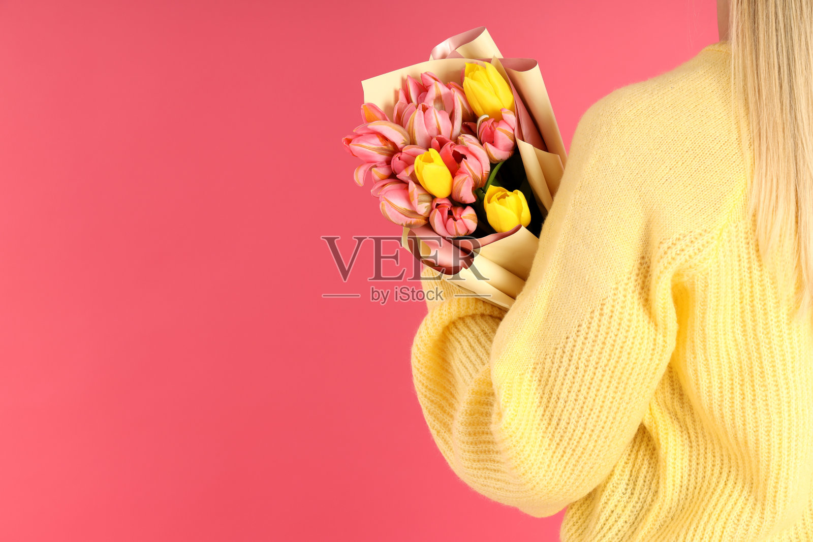 一名女子手持一束粉红色背景的鲜花照片摄影图片