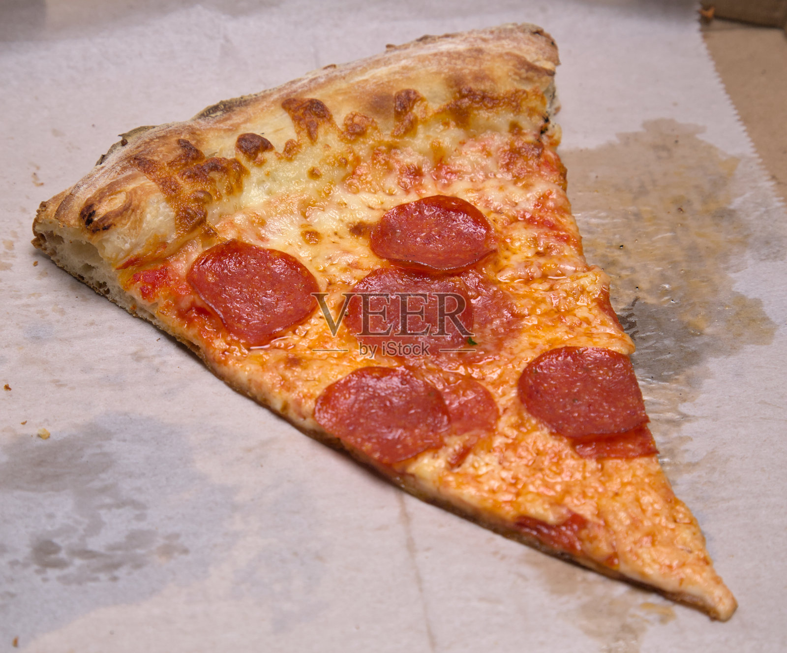 纽约市风格披萨片(意大利辣香肠)在油腻的羊皮纸照片摄影图片