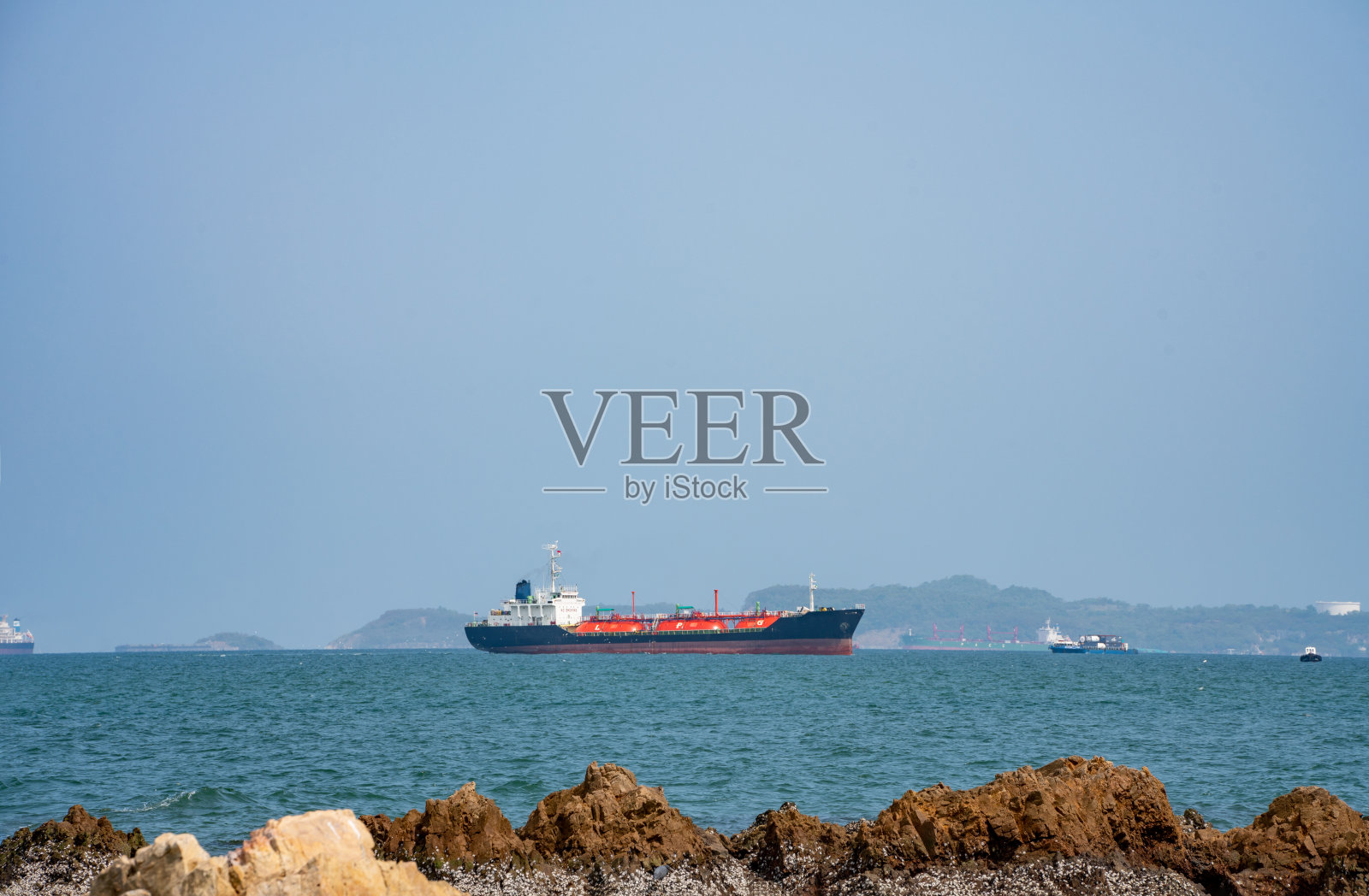 在海上航行的天然气船、液化石油气船。石油产品船只靠近礁石嶙峋的岩石。照片摄影图片