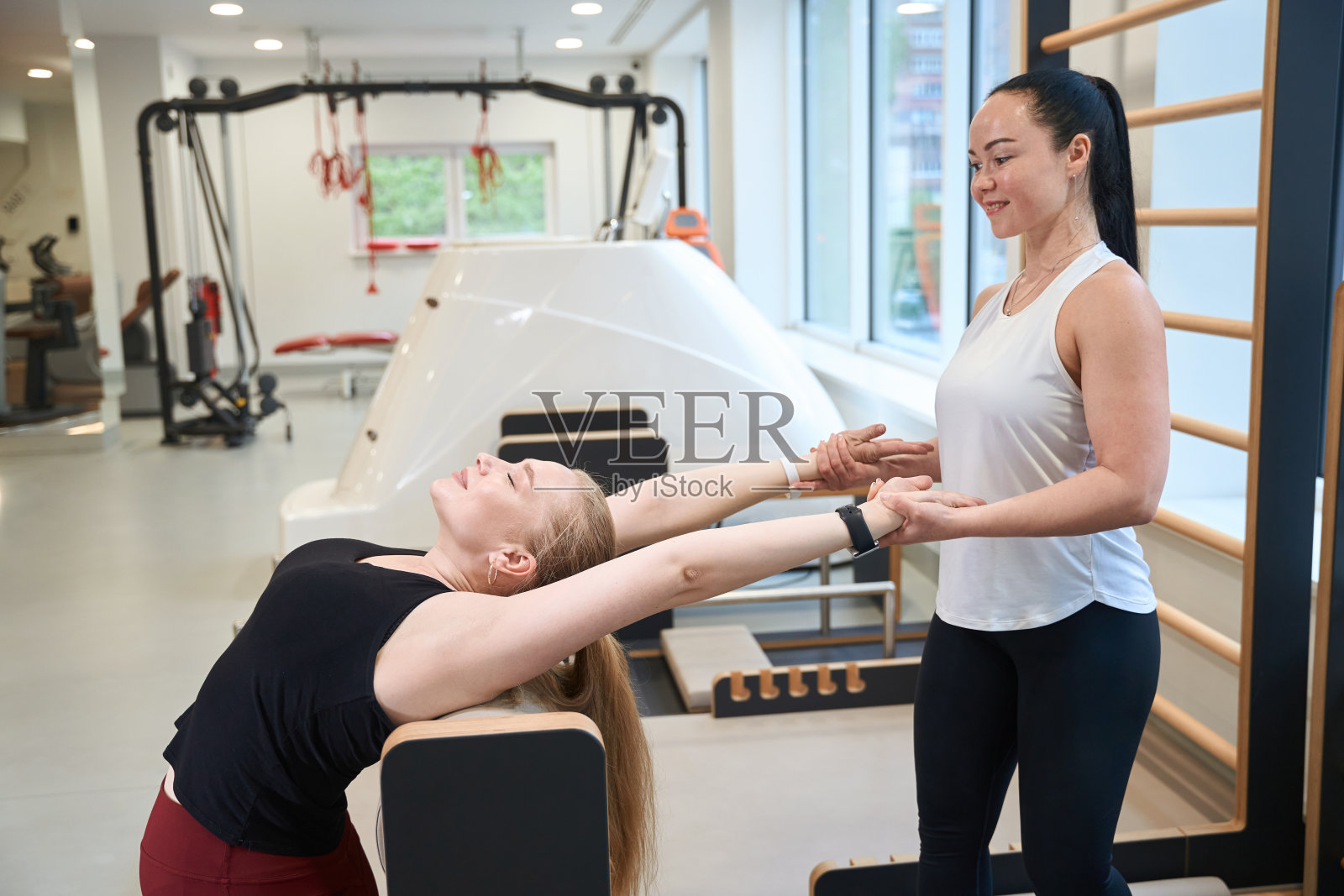 金发女郎在教练的指导下做伸展运动照片摄影图片