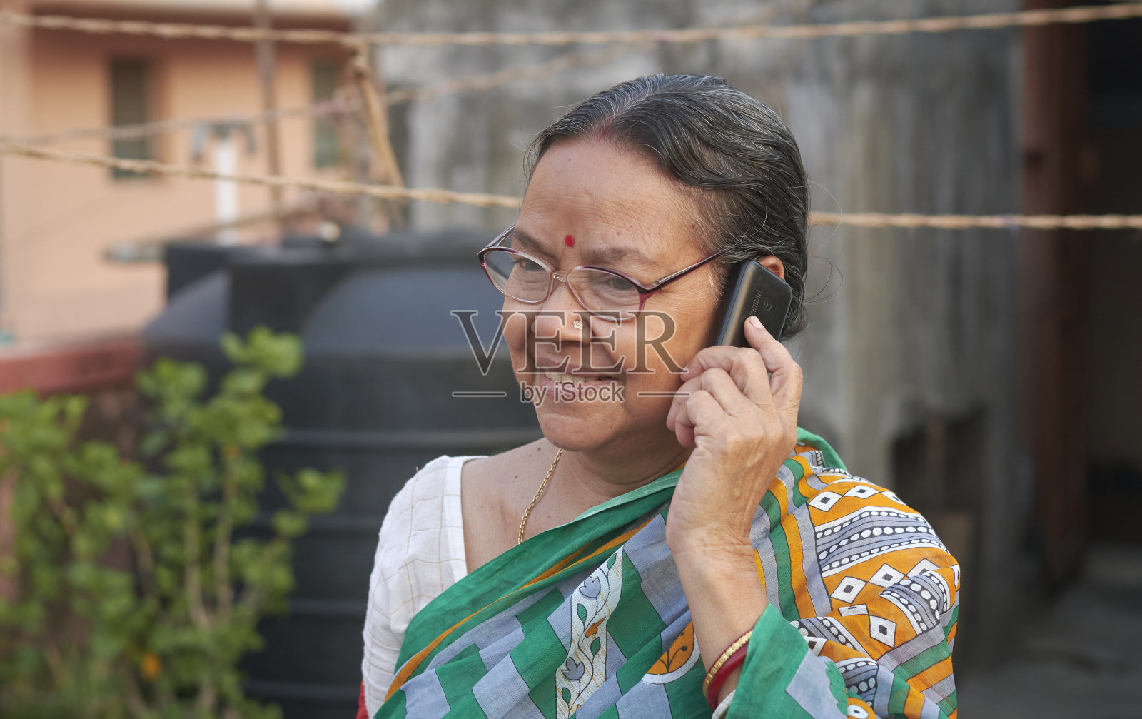 一个看起来很快乐的孟加拉老妇人的肖像,正在用普通的电话交谈照片摄影图片