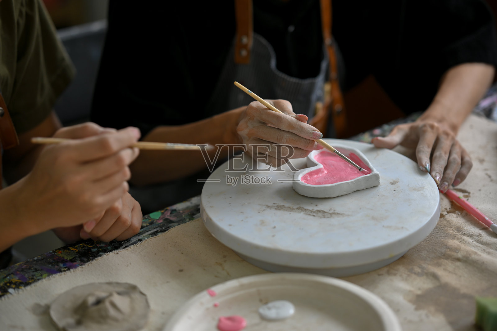 在创意手工艺工坊里,一位男子正在享受着绘制陶瓷心盘的乐趣照片摄影图片