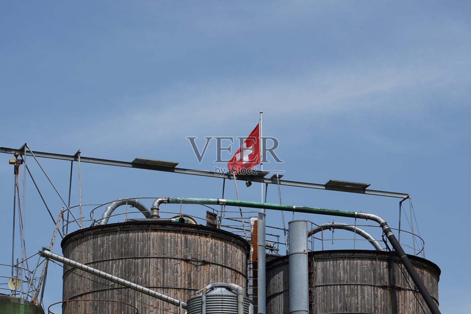 蓝色的天空上有瑞士国旗的木制筒仓。副本的空间。照片摄影图片