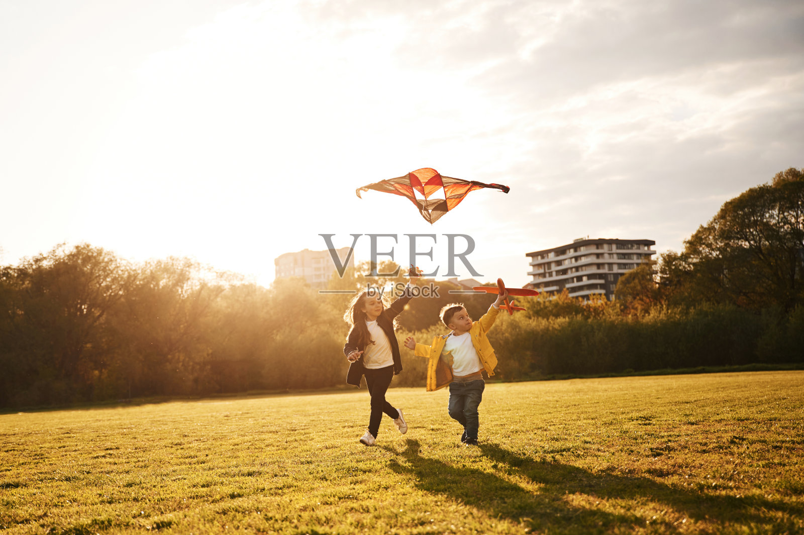 两个孩子在夏天的操场上玩风筝照片摄影图片