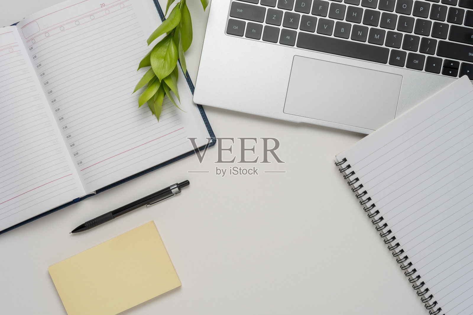 现代白色办公桌椅配有笔记本电脑、笔记本等用品。俯视图,平铺。照片摄影图片