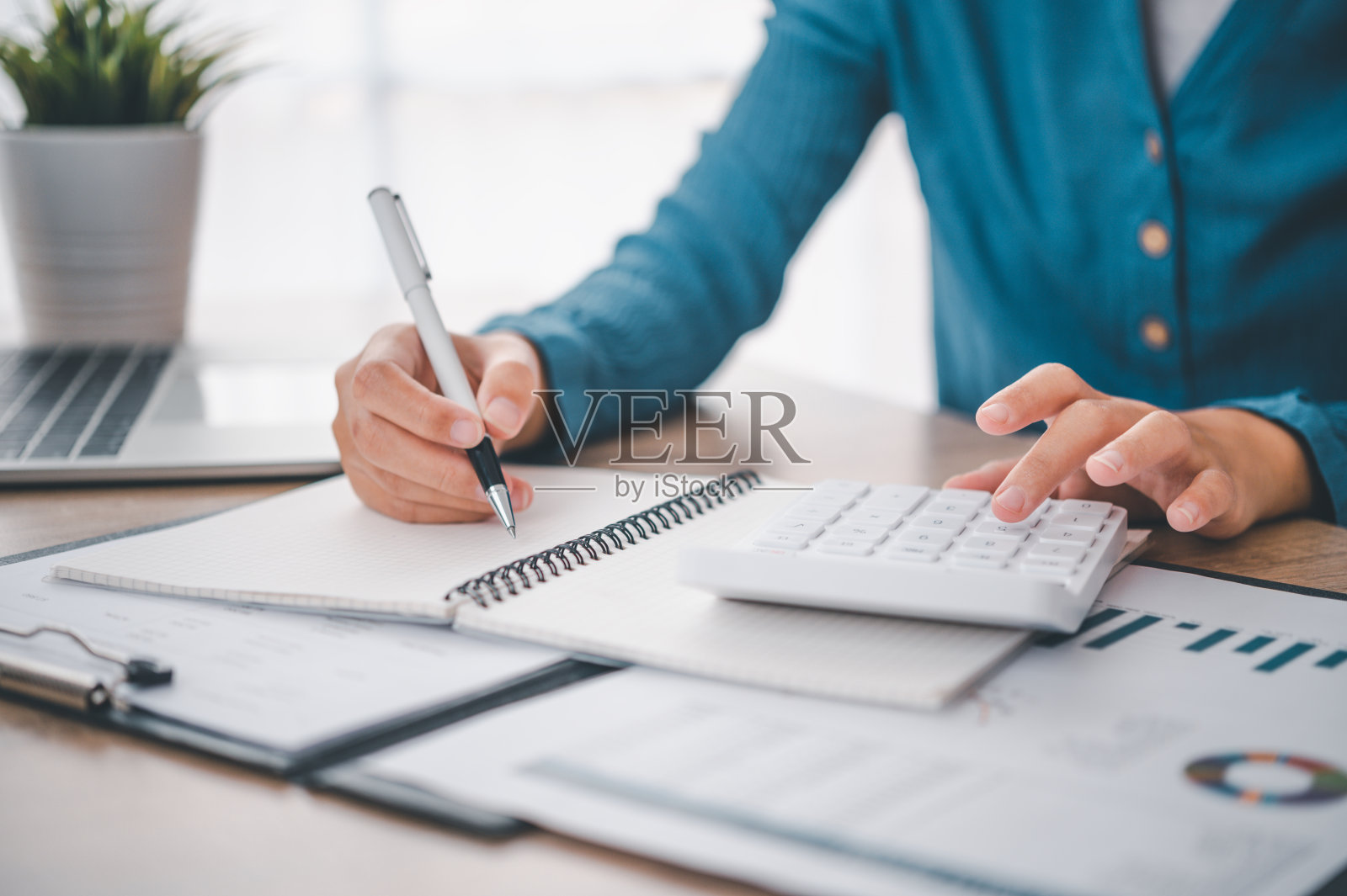 在财务会计概念办公室里,商务人士正坐在一个带有图表的计算器前照片摄影图片