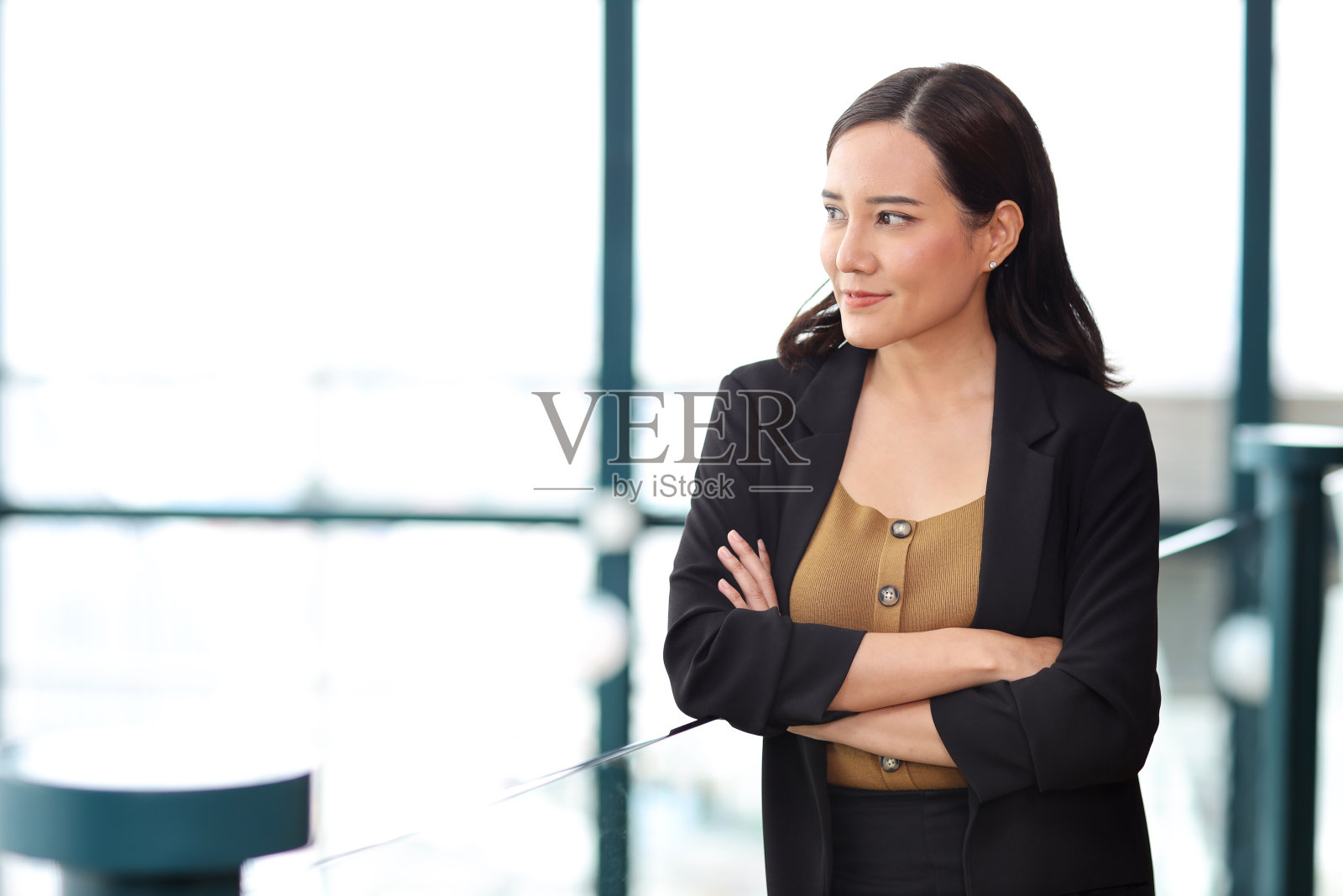 自信的年轻亚洲女商人在现代办公大楼和城市背景下,双臂交叉站在商务会议上,脸上带着幸福的微笑,研究和规划工作照片摄影图片