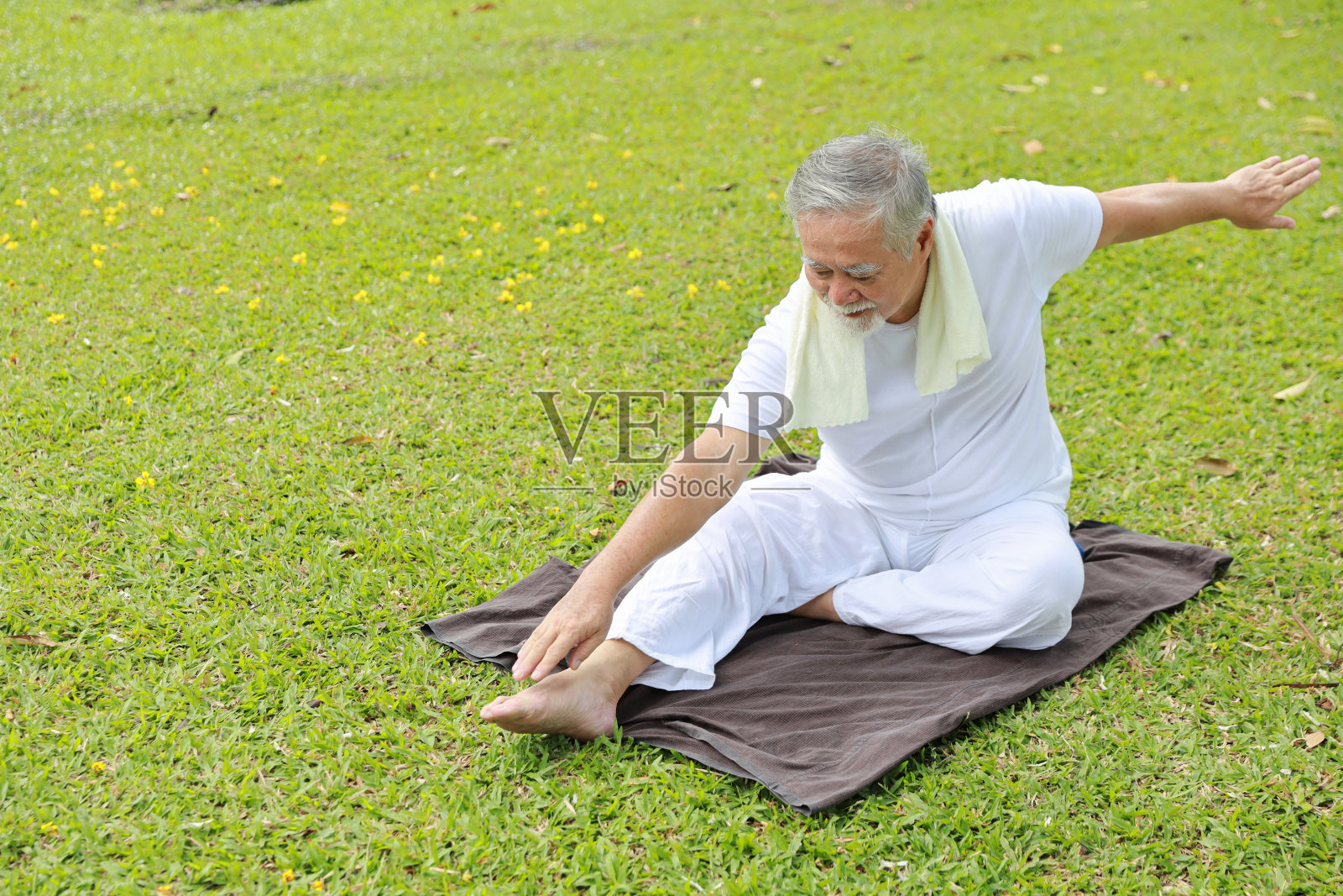 亚洲老年人退休后在公园户外坐在瑜伽垫上练习瑜伽、伸展运动、太极训练和冥想,以保持健康。快乐老年人户外生活理念照片摄影图片