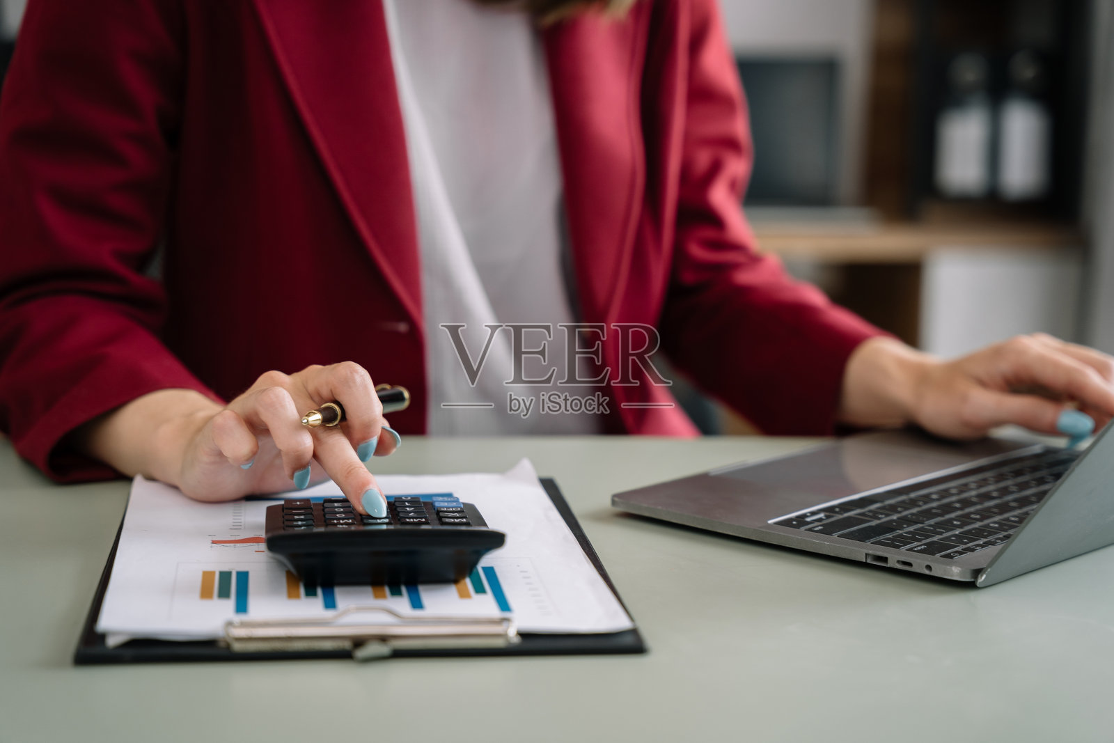 女人们正在用计算器计算办公室收入。照片摄影图片