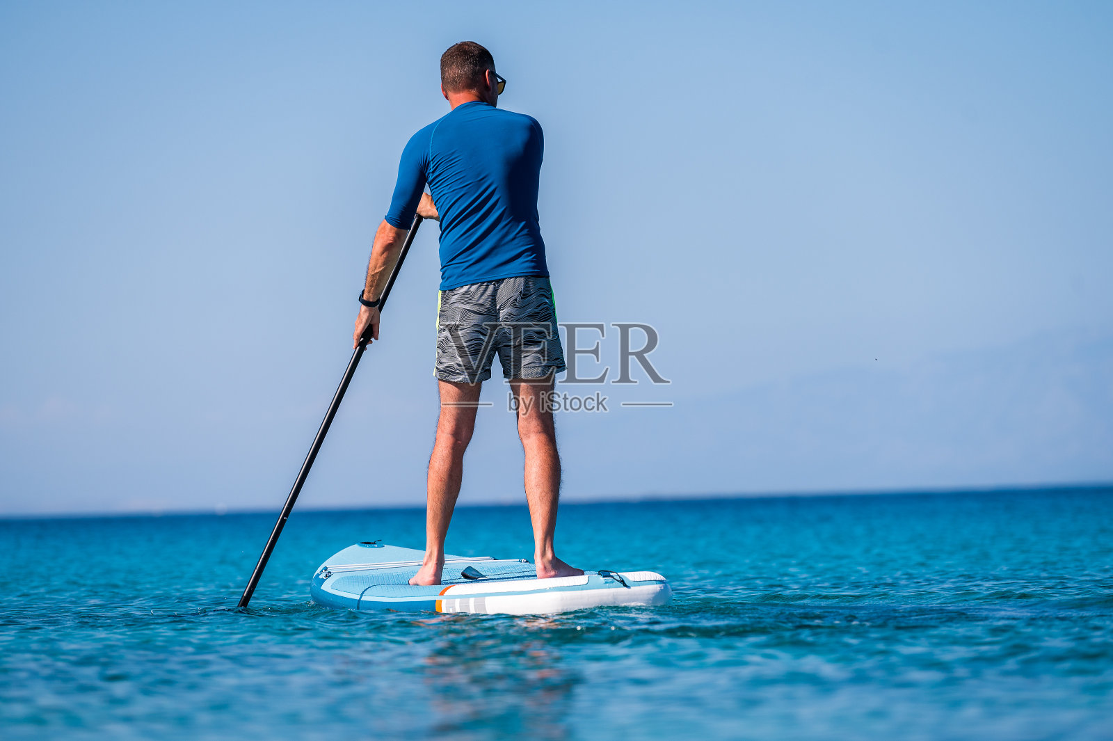 度假时骑SUP的人站起来划桨。照片摄影图片