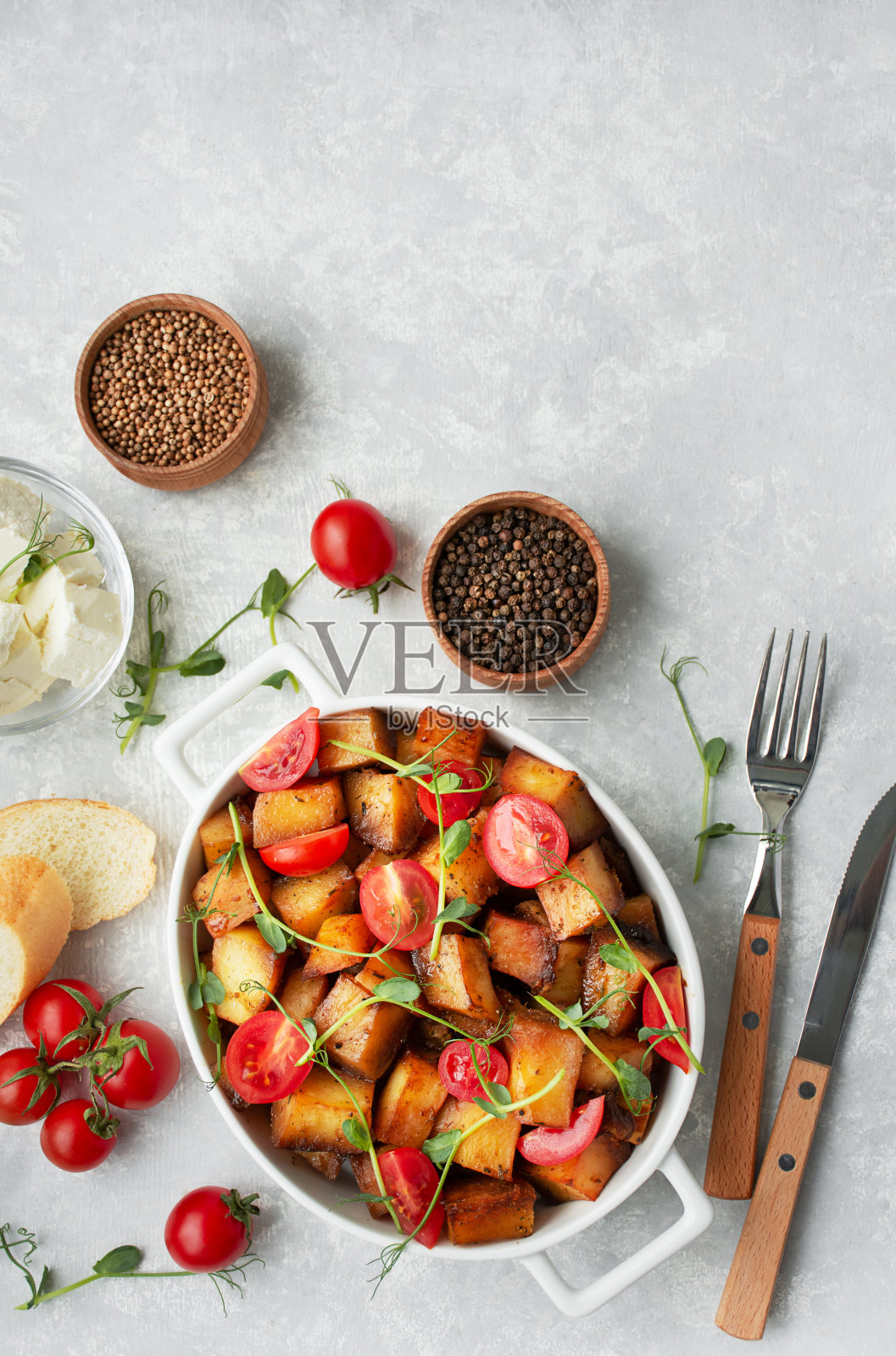 在浅色背景下的陶瓷盘子里,烤土豆配上新鲜的西红柿和蔬菜。从上面看。副本的空间。照片摄影图片