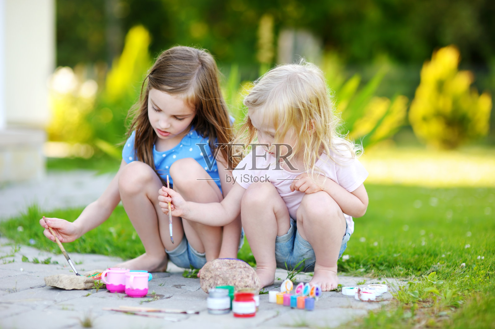 两个可爱的小姐妹一起在石头上画画照片摄影图片