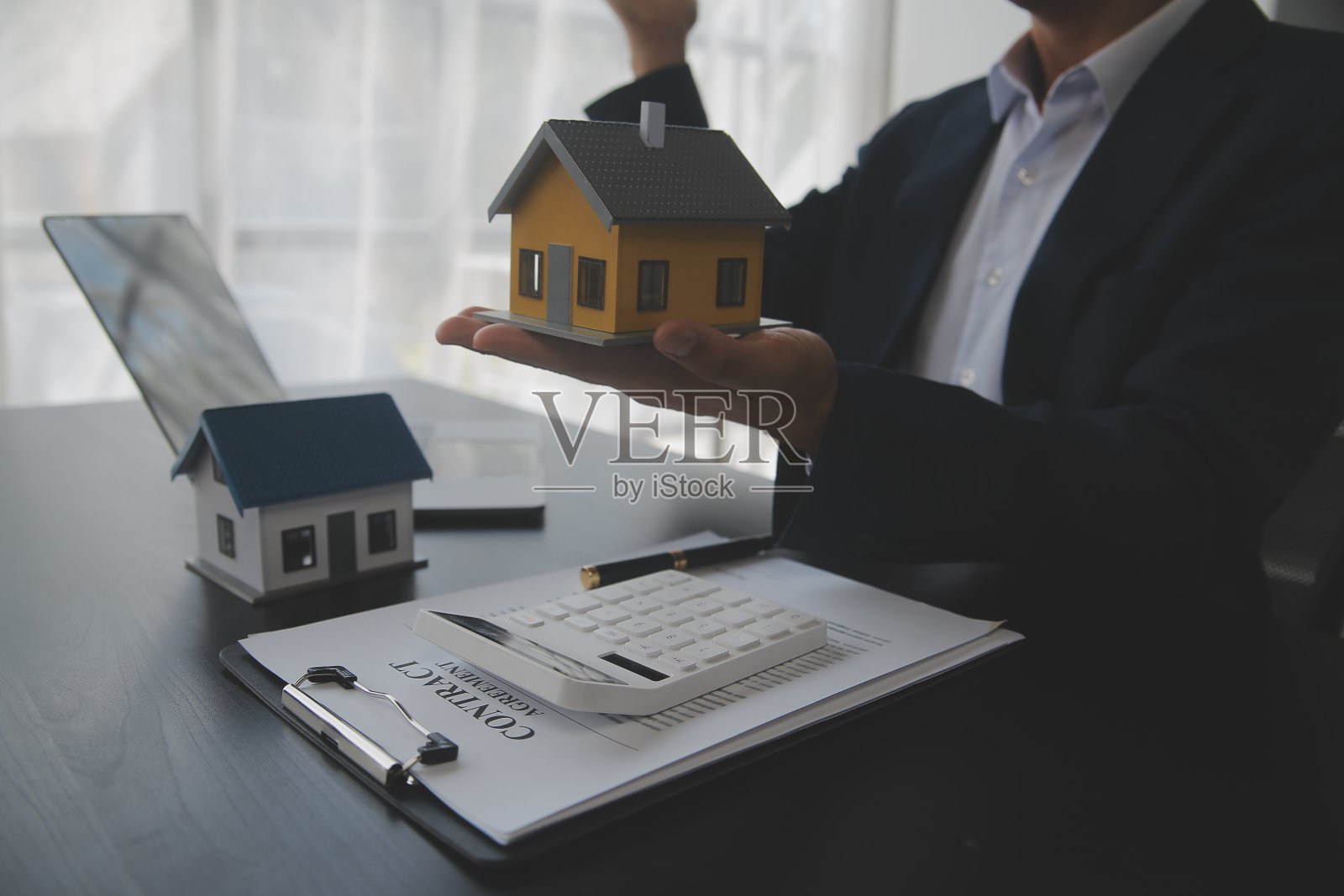 房地产经纪人向客户提出并咨询决策签订保险合同,买卖房屋模型,有关按揭贷款报价和房屋保险照片摄影图片