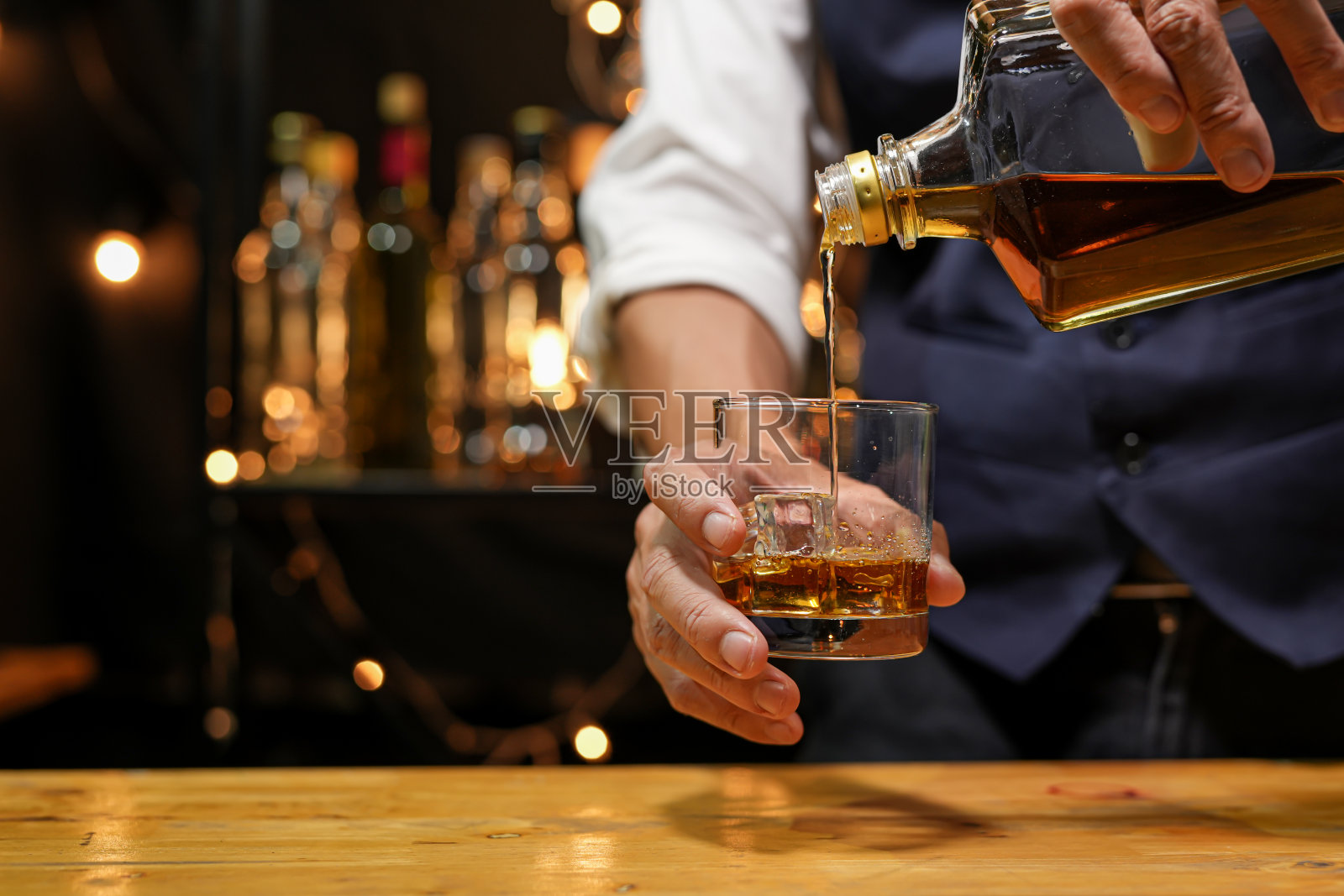 调酒师在吧台上倒威士忌,照片摄影图片