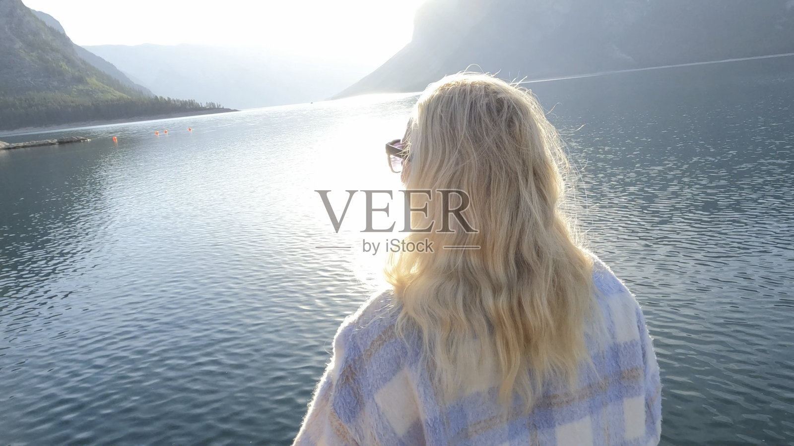 一位老妇人沿着木制的湖码头散步照片摄影图片