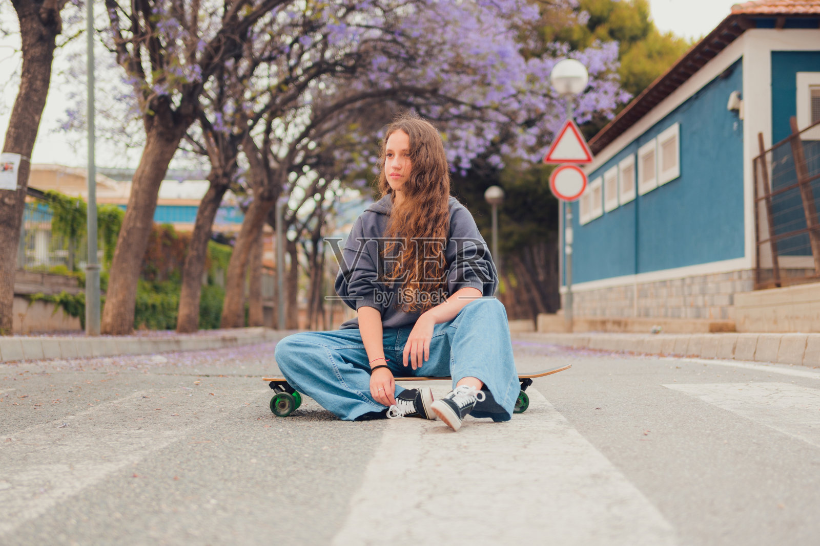 年轻女子坐在路上的滑板上照片摄影图片