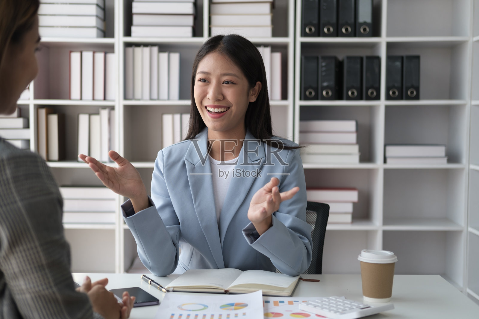 年轻聪明的女商人在办公室里和同事讨论她的项目。照片摄影图片