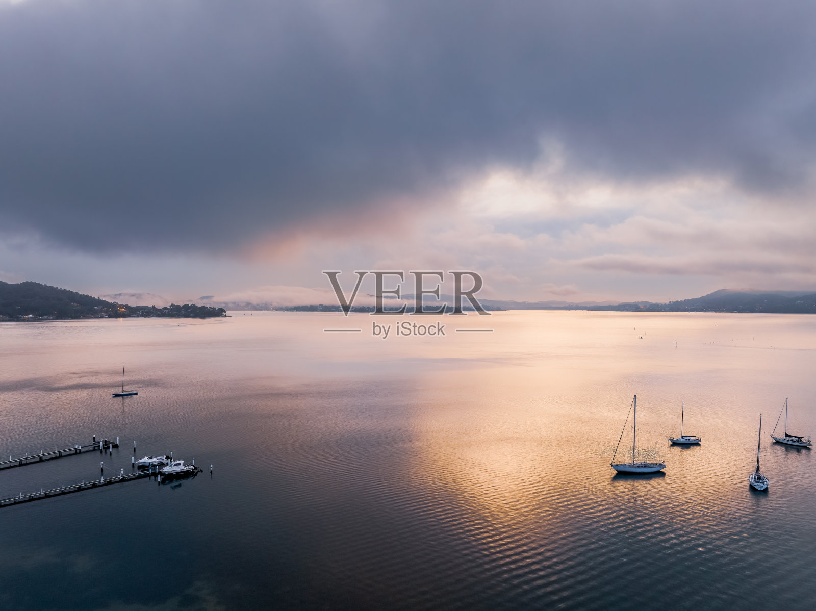 雾蒙蒙的日出和小船在水面上照片摄影图片