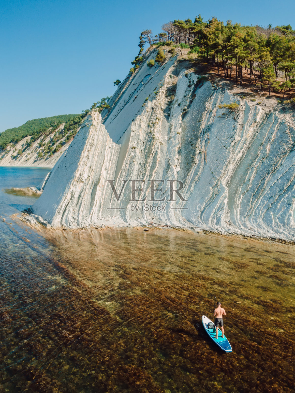 站在桨板上的旅行者在海上欣赏令人难以置信的风景。鸟瞰图照片摄影图片