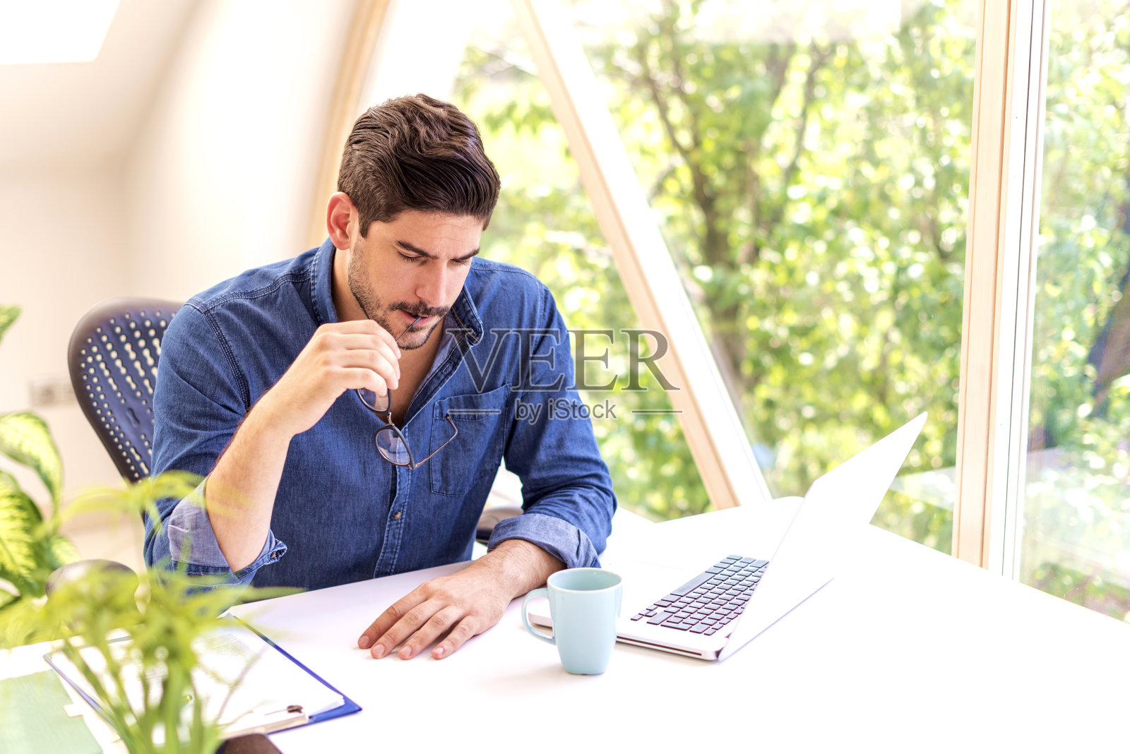 紧张的商人坐在办公桌旁,用笔记本电脑工作照片摄影图片