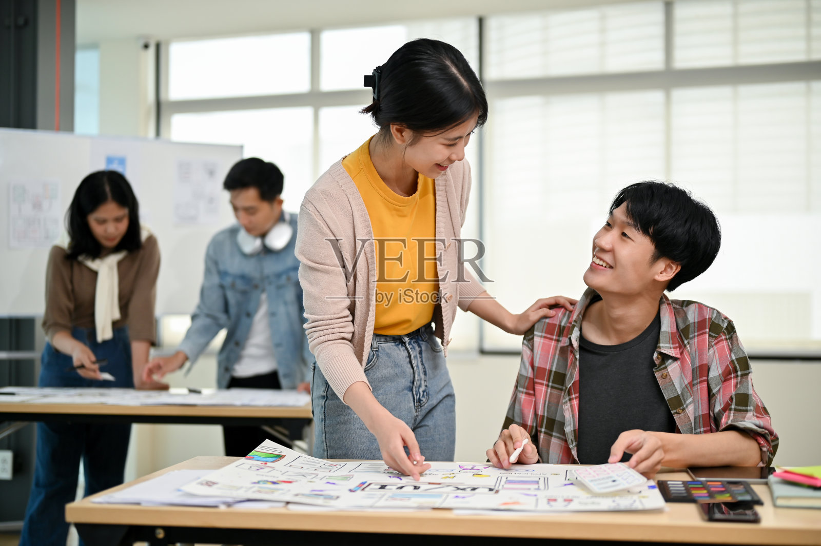 一位女性平面设计师正在办公室里与一位男性开发人员交谈和工作。照片摄影图片