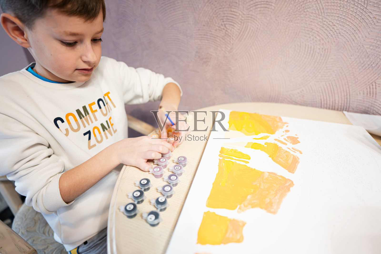 左手男孩正在家里用水粉画数字。舒适区。照片摄影图片
