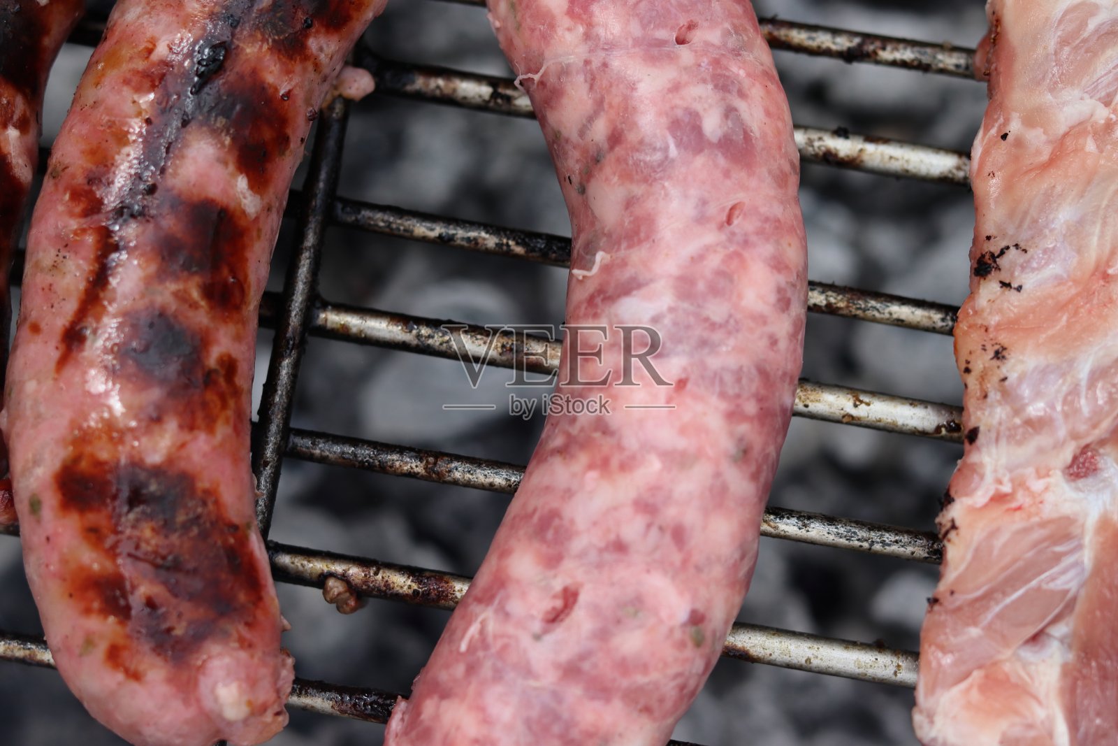 香肠和猪肉在烤架上烤的特写。照片摄影图片