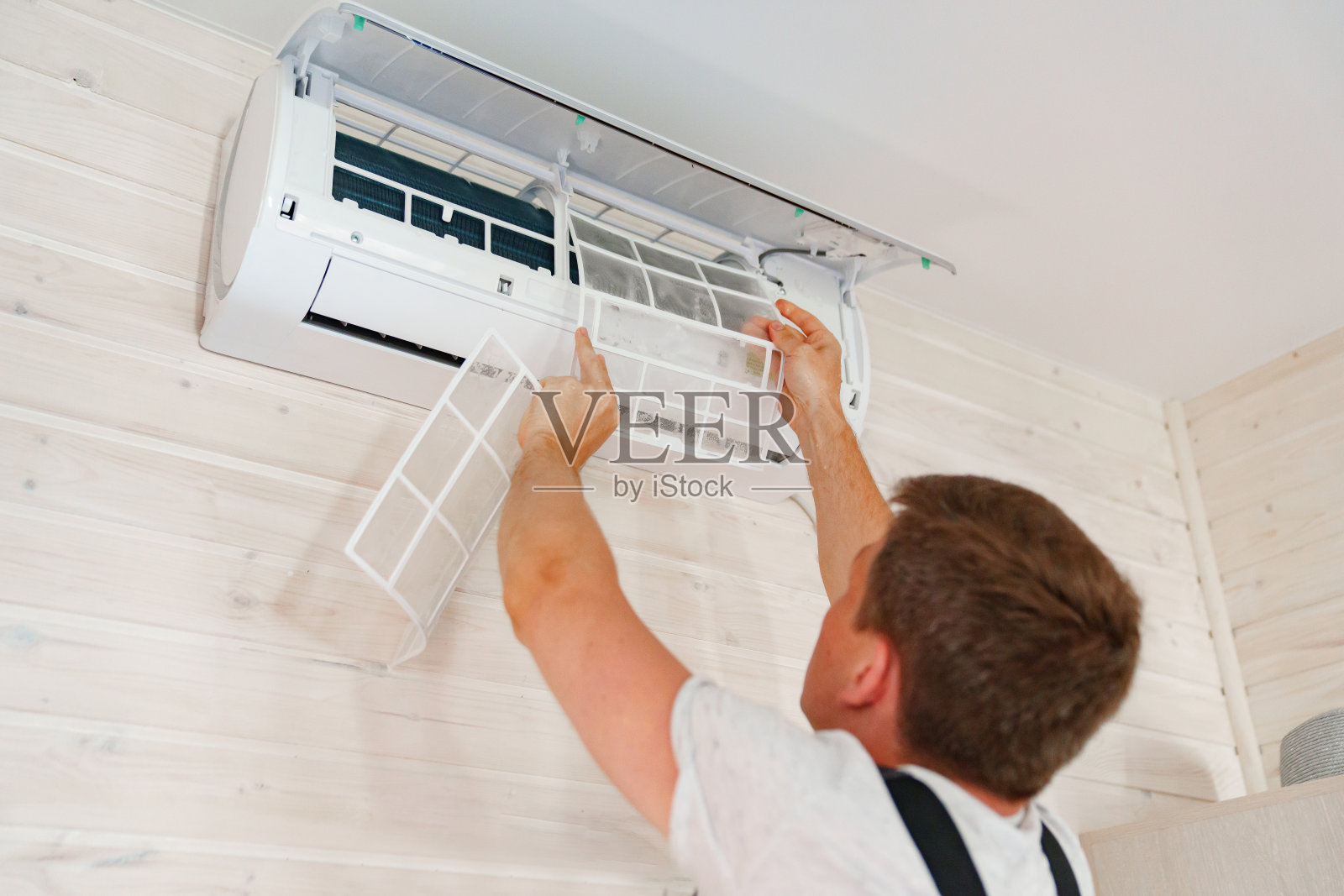 一名男子更换并清洗空调上的空气净化器过滤网。照片摄影图片