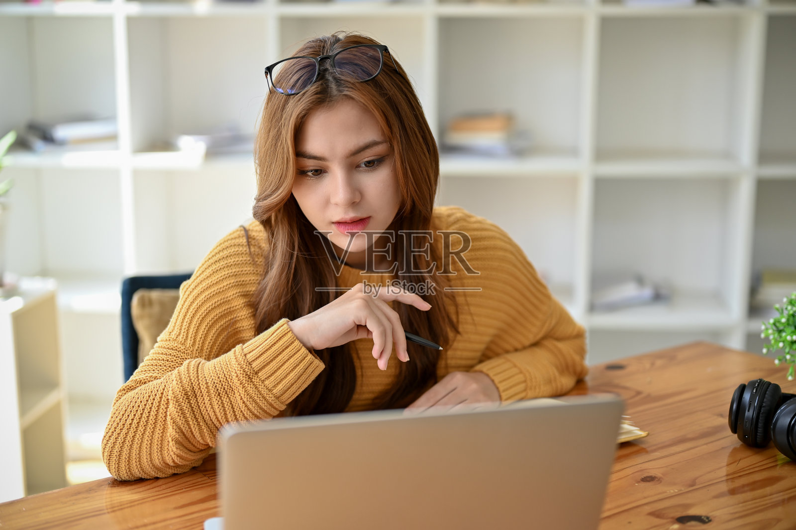 一位美丽而严肃的年轻亚洲女大学生坐在她房间的工作桌旁照片摄影图片