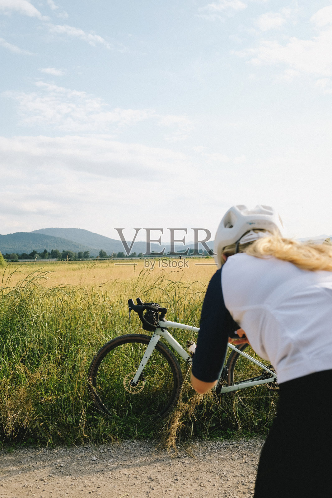 年轻女子骑着沙砾自行车停在乡间小路上照片摄影图片