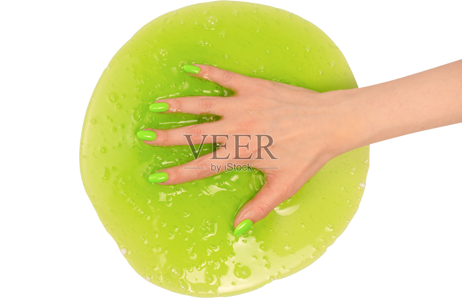 女人手里拿着绿色黏液玩具,白色背景上有绿色的指甲。照片摄影图片