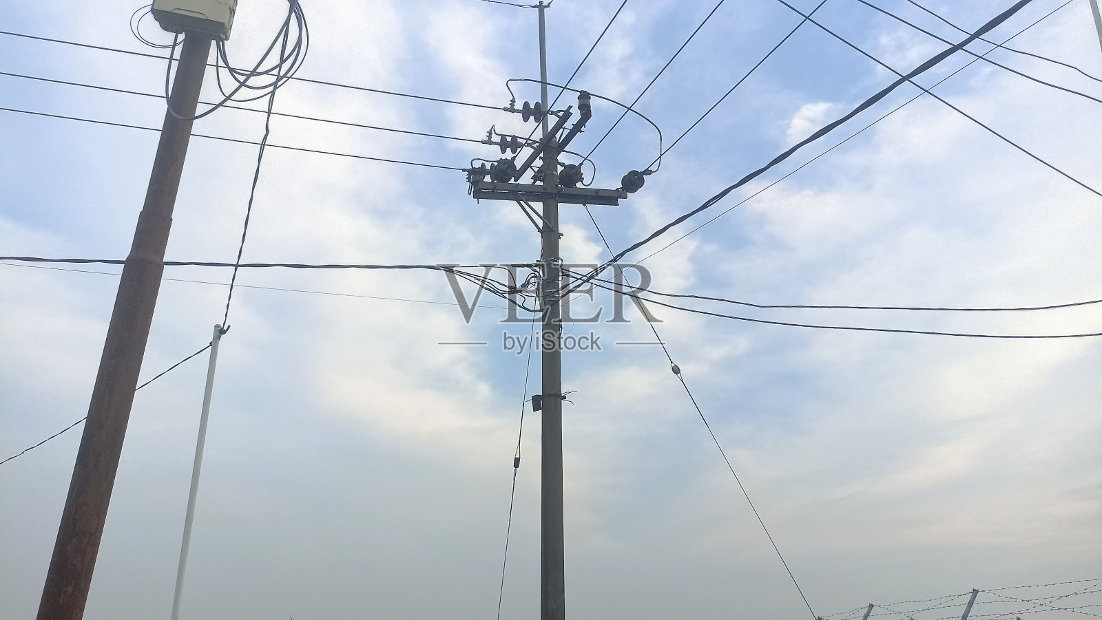 带电线电缆的电线杆。,映衬着蓝天的多云和柔和的焦点。多云天空下的电线杆,照片特写照片摄影图片