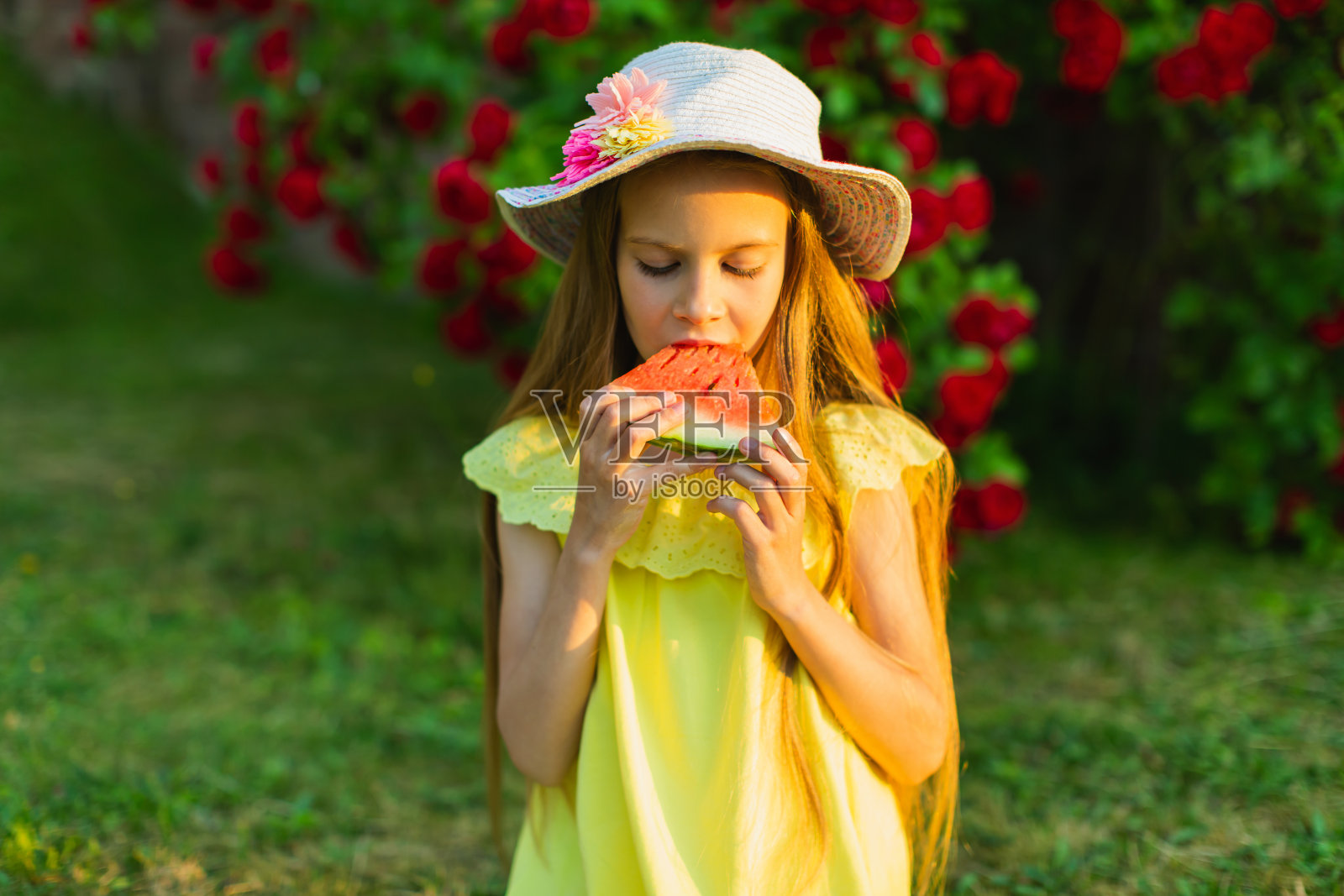 快乐的金发女孩穿着黄色的衣服,拿着一块西瓜。夏天的生活方式。的童年。照片摄影图片