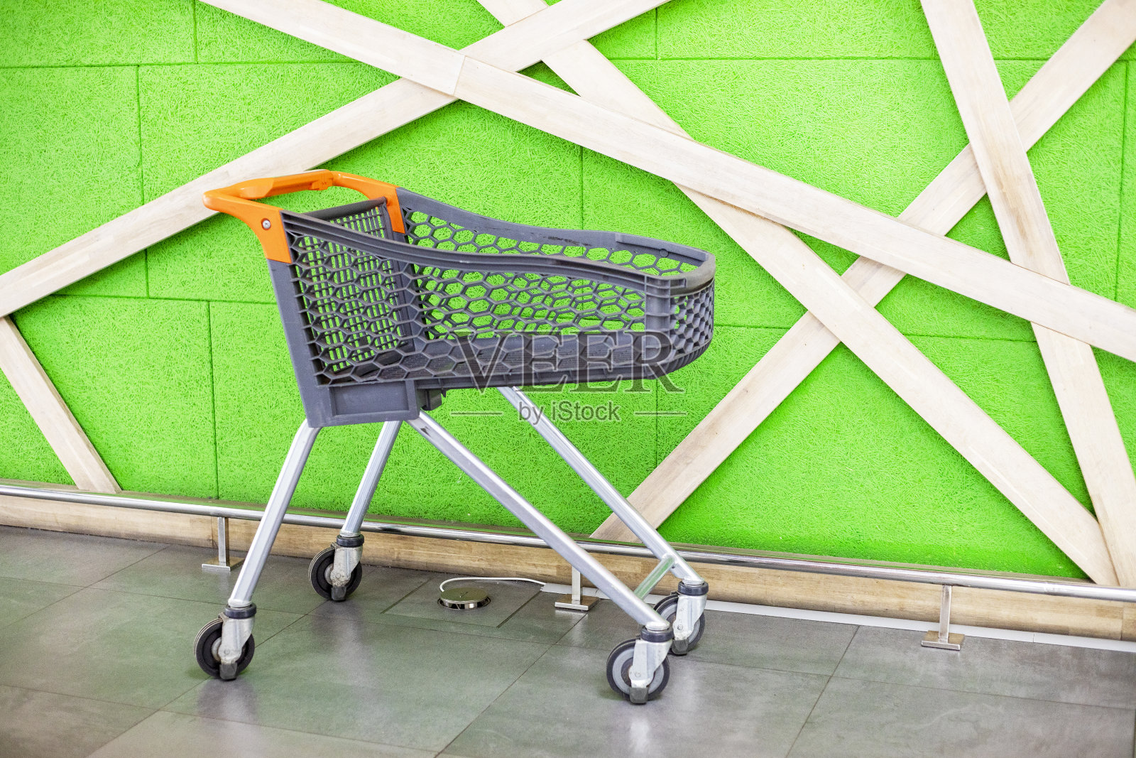 购物中心的绿墙背景下的空塑料手推车。一周购物照片摄影图片