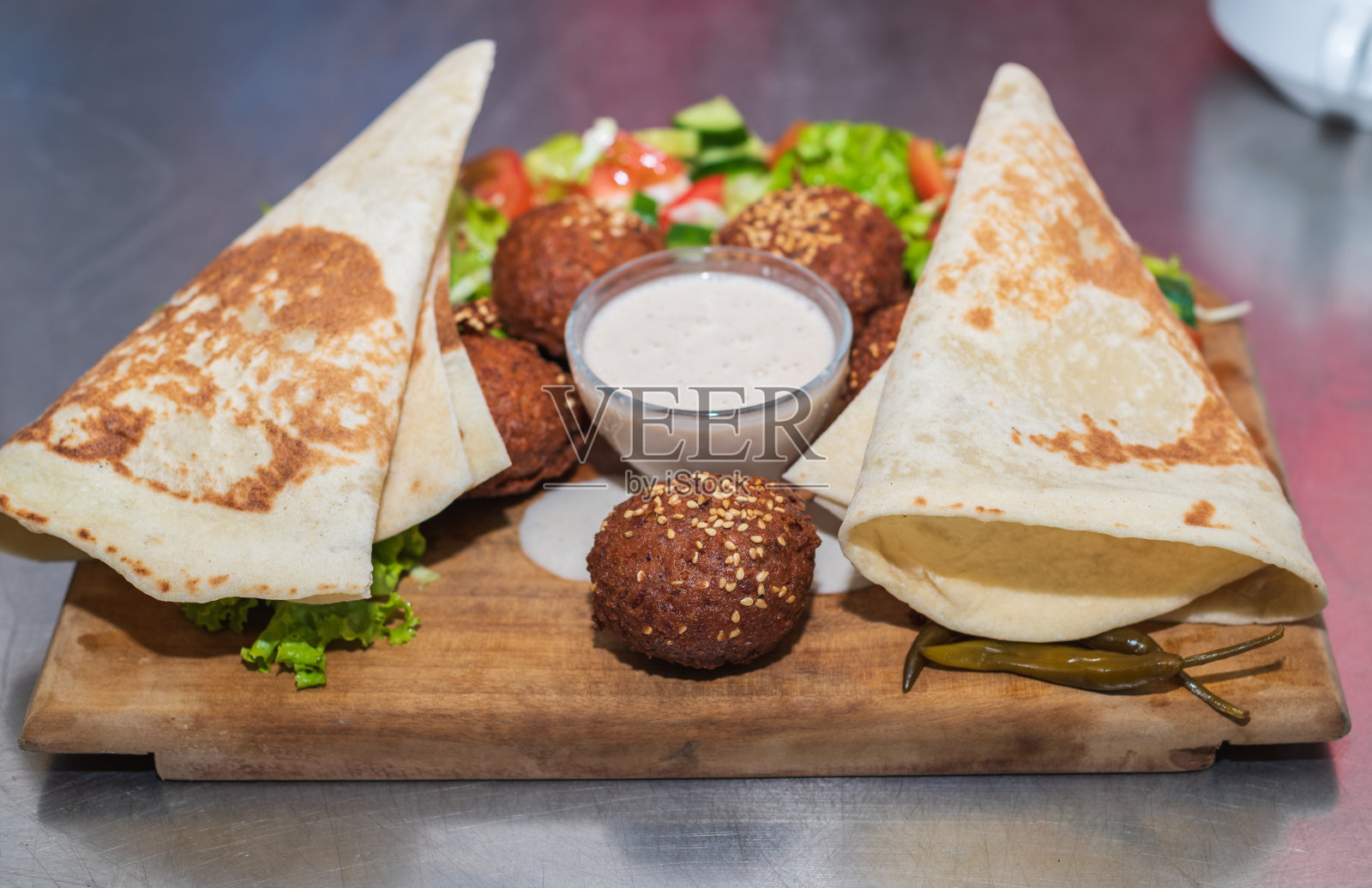 用木制盘子展示中东黎巴嫩菜沙拉三明治。玉米饼,蔬菜沙拉,还有芝麻酱。照片摄影图片