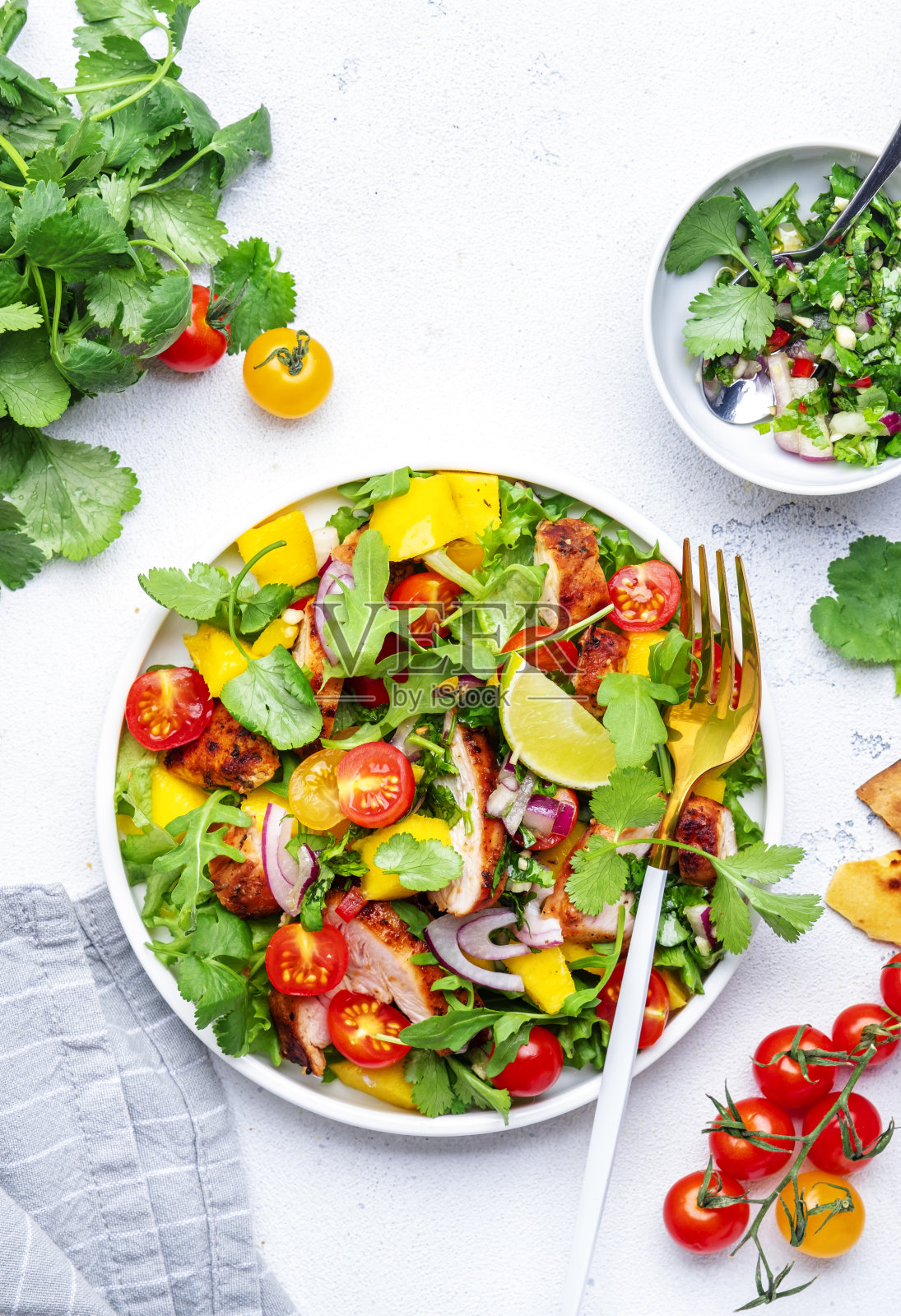美味的沙拉,烤鸡和芒果沙拉,番茄,香菜,洋葱和生菜在墨西哥风格,白色厨房餐桌背景,俯视图照片摄影图片
