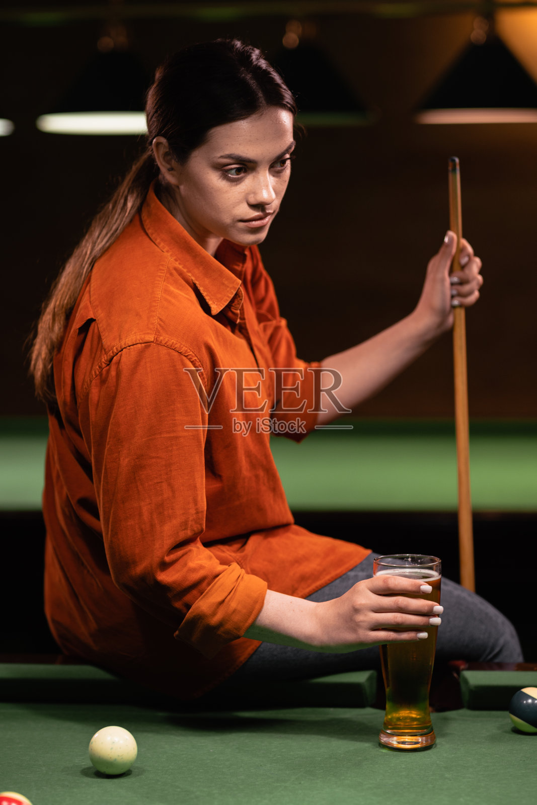 年轻美女坐在台球桌上喝啤酒的画像照片摄影图片