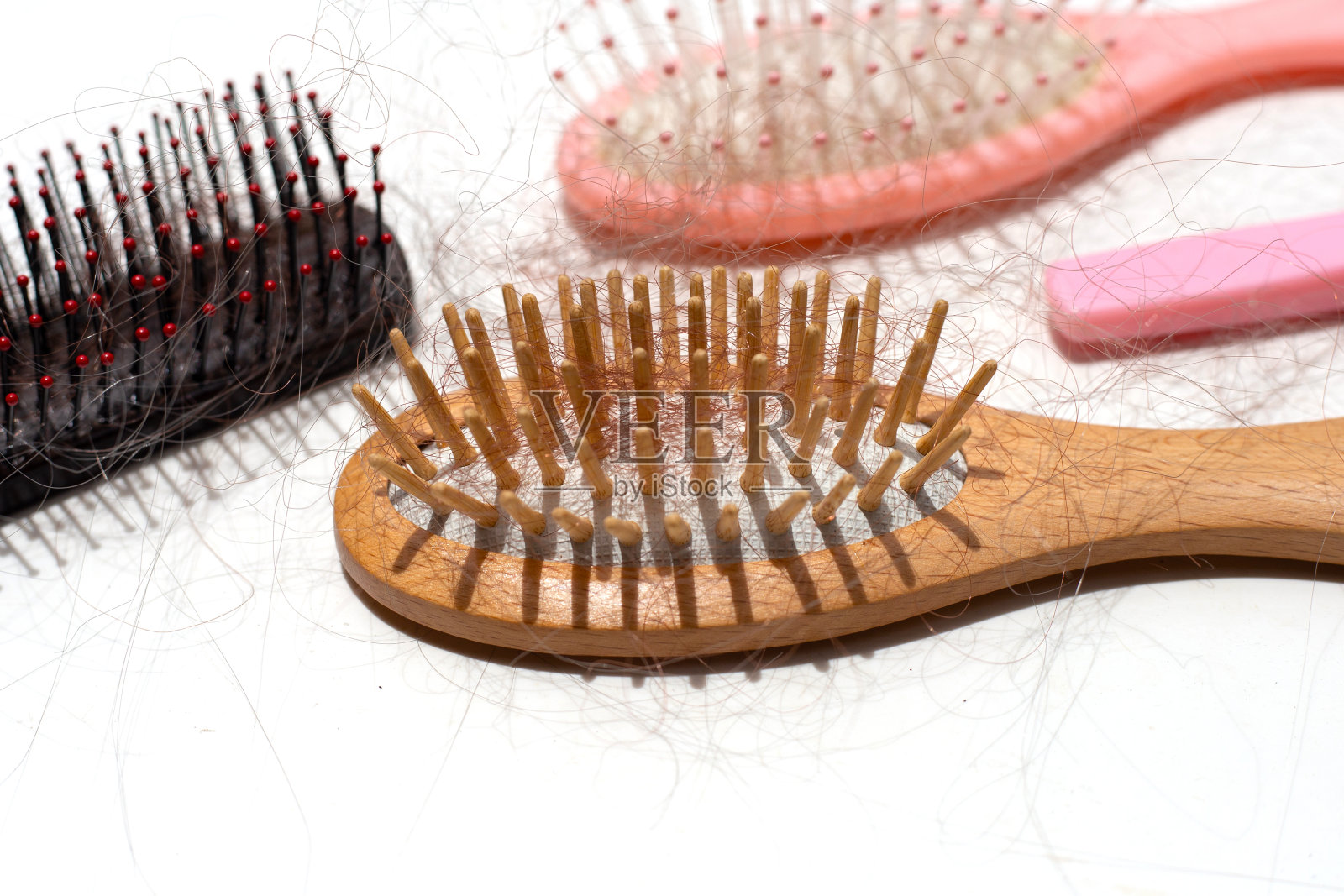 在白色的背景上,头发脱落在梳子上。照片摄影图片