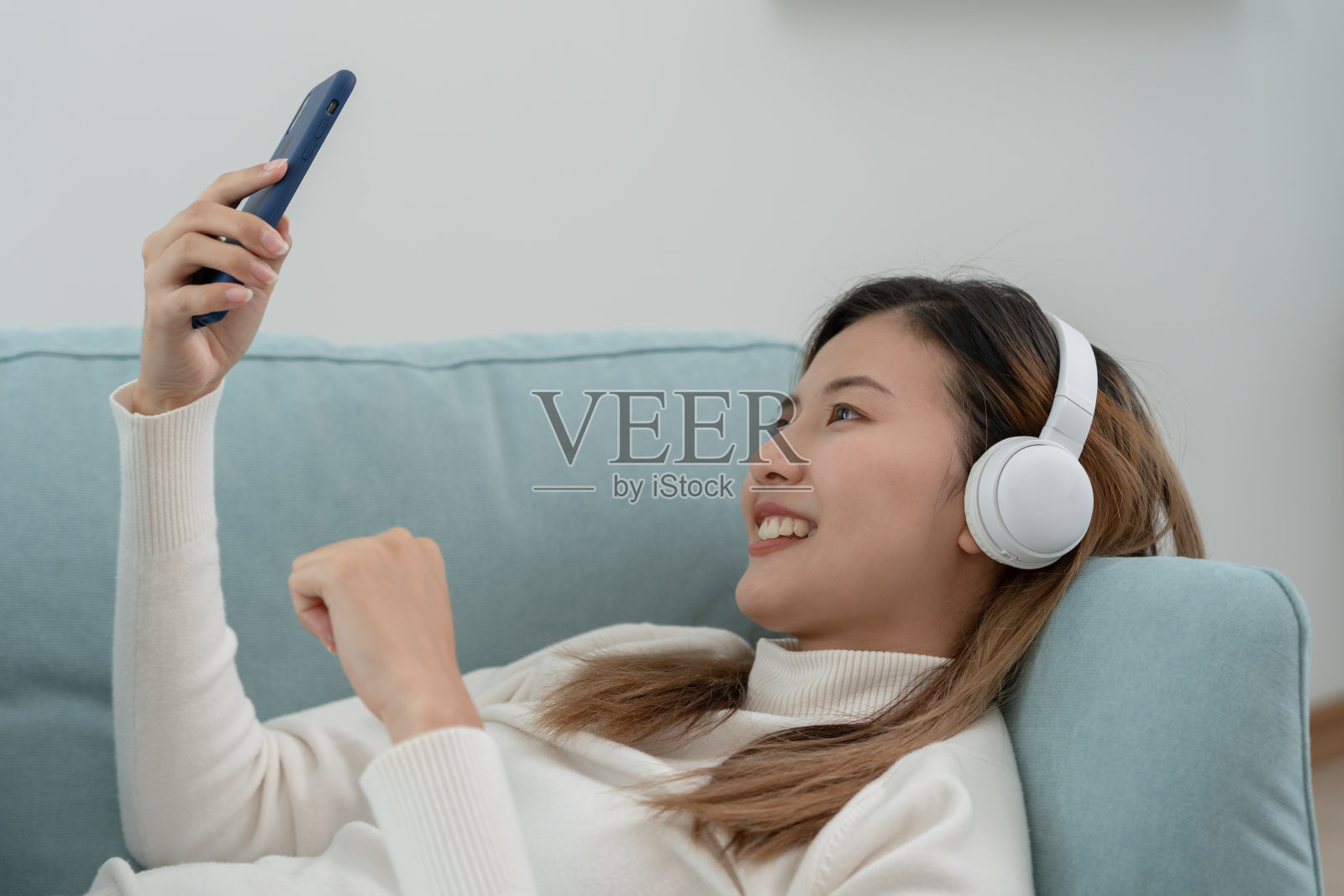 快乐的年轻亚洲女性坐在无线耳机享受音乐,玩得开心,听音乐,举起他的手臂,跳舞喜欢的歌曲,享受酷的配乐,快乐的生活,娱乐照片摄影图片