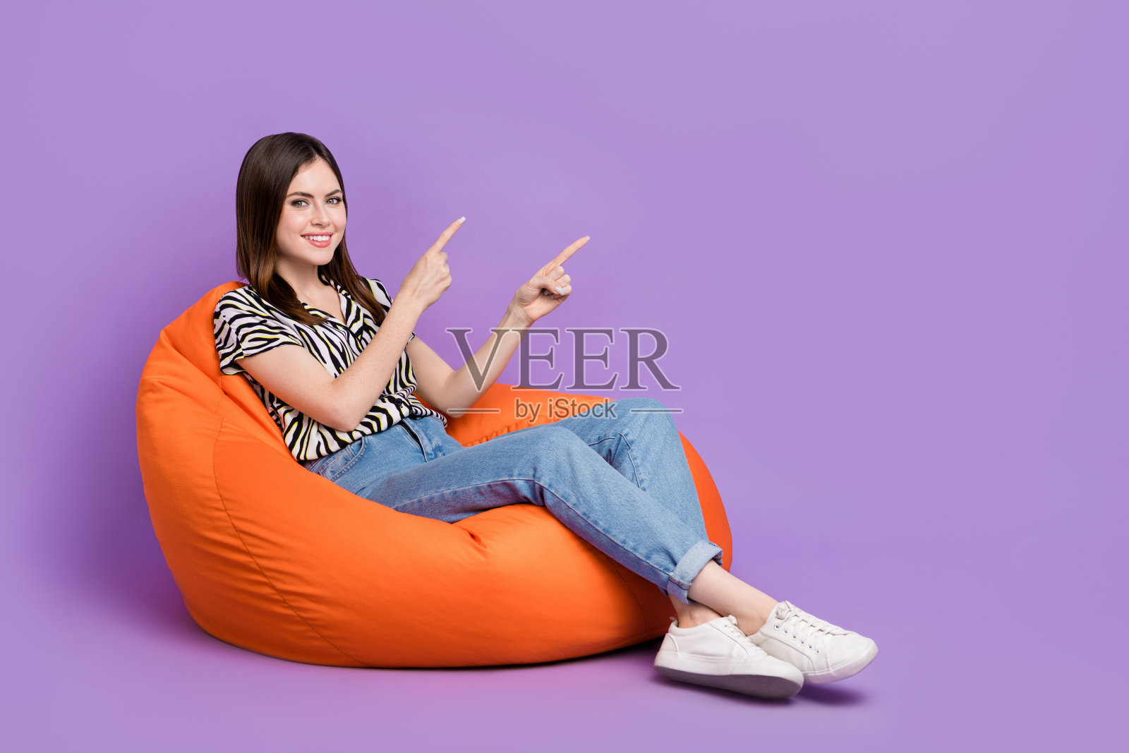 相当积极的人的全长照片,坐在舒适的袋子表明手指空白空间孤立的紫色背景照片摄影图片