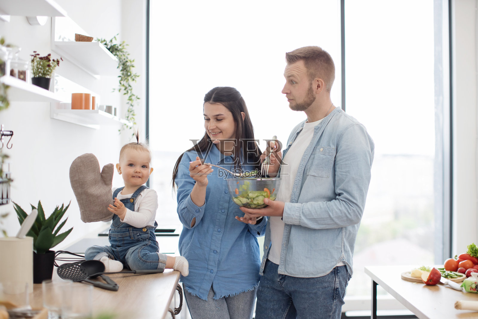 父母看着孩子玩厨房手套照片摄影图片