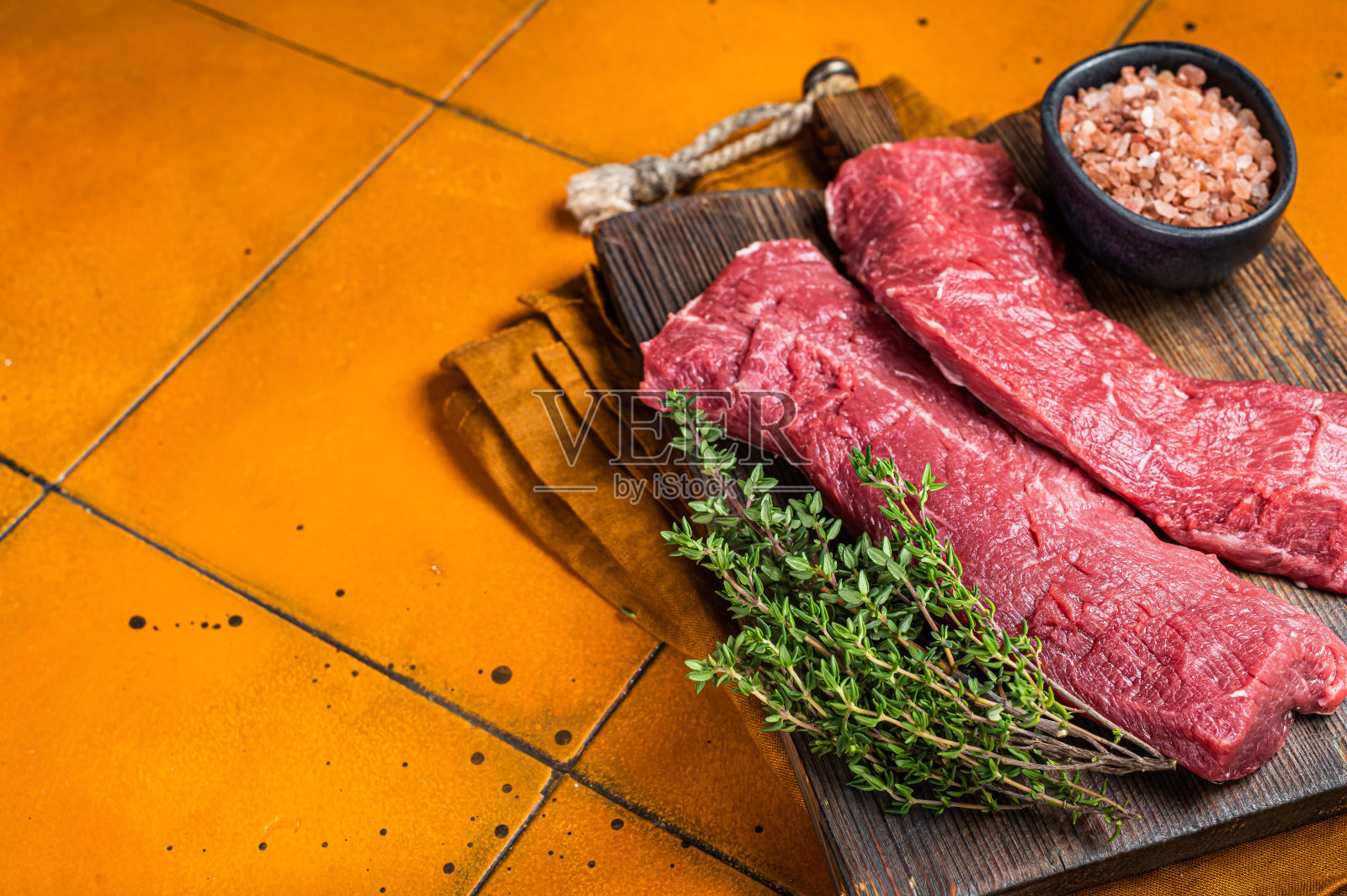 肉桌与生羊里脊片,羊里脊肉与百里香。橙色背景。前视图。本空间照片摄影图片