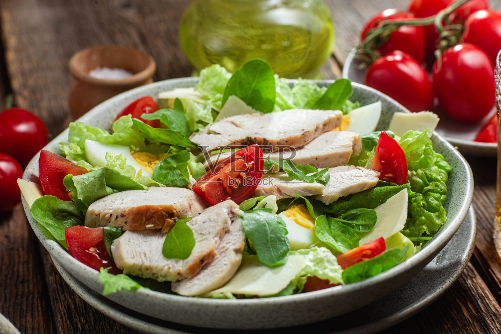 鸡柳沙拉,鸡蛋,西红柿和奶酪在一个盘子里。凯撒沙拉照片摄影图片