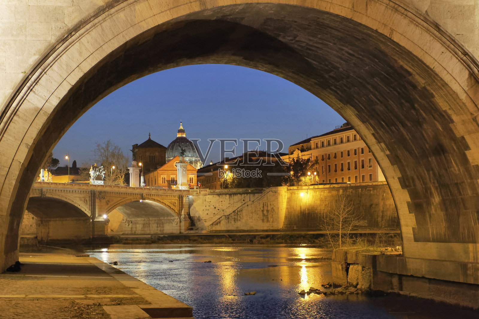 从圣安杰洛桥的拱门看圣彼得大教堂圆顶的夜景照片摄影图片