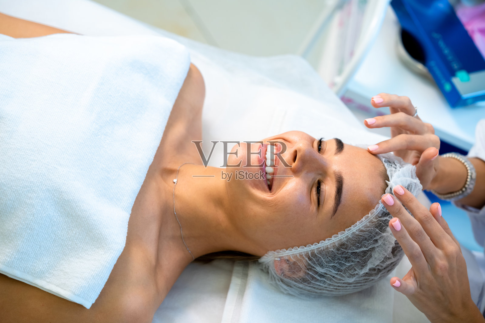 美容师将一次性帽戴在女士的头上,为客户准备整容手术照片摄影图片