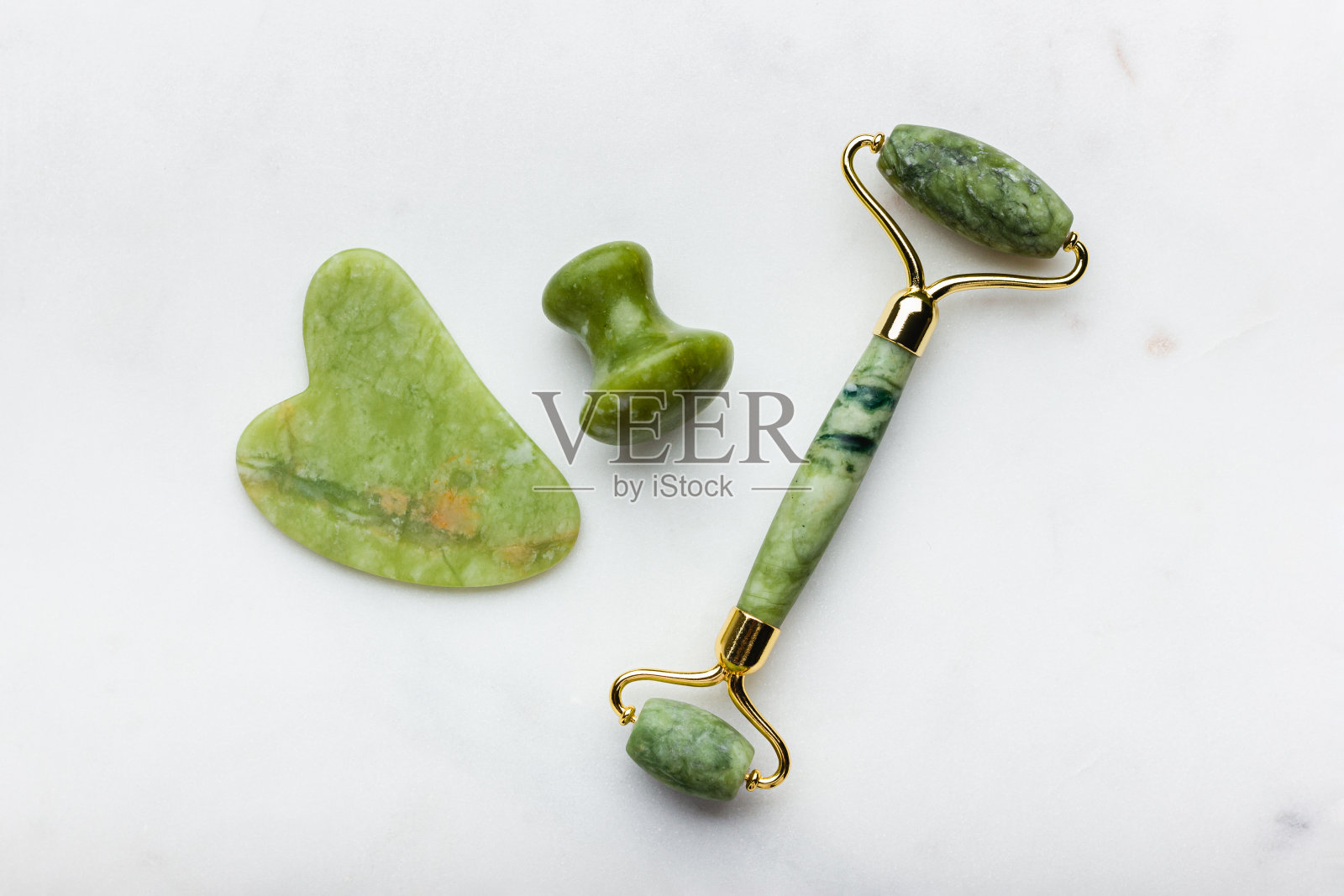 白色大理石上的青玉滚轮按摩器。照片摄影图片