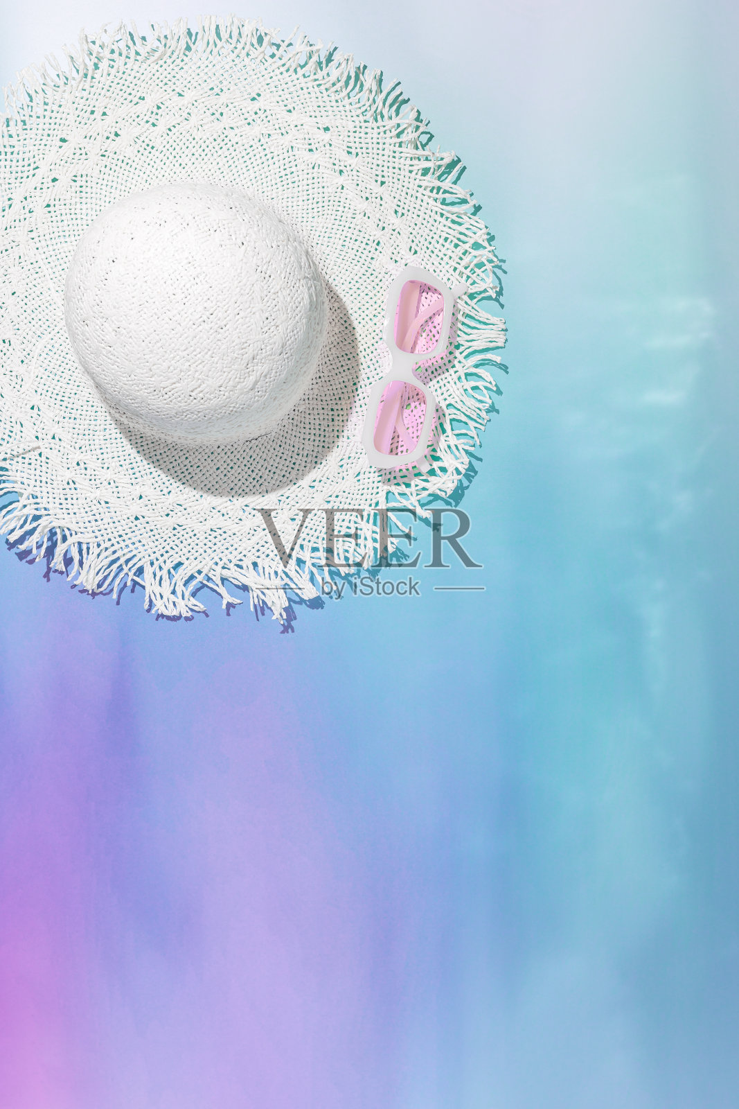 夏季垂直平躺与白色太阳帽和玫瑰色太阳镜模糊的霓虹色渐变背景。创意唯美的静物暑假写真,抽象的海水照片摄影图片