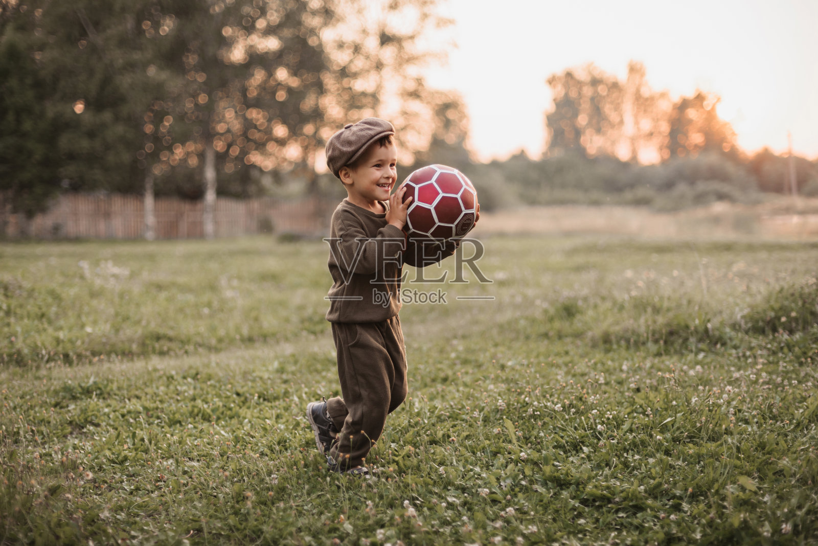 积极的休闲活动。一个男孩正在乡下的户外踢足球。照片摄影图片