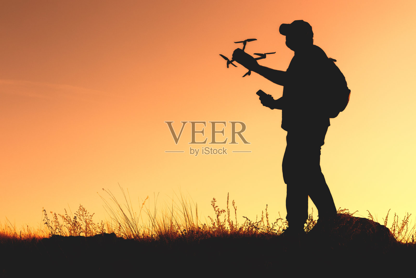 一个拿着四轴飞行器和智能手机的男人的剪影照片摄影图片